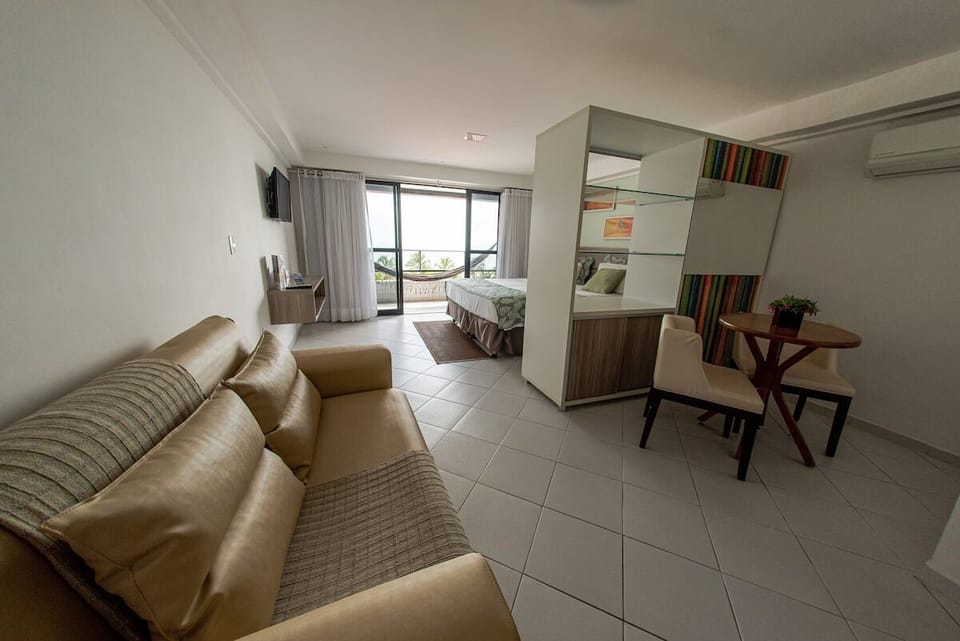 Unwind in a spacious studio with bed, sofa, and ocean light.