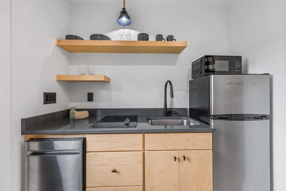 Compact kitchen featuring modern appliances, wooden shelves, and sleek countertops.