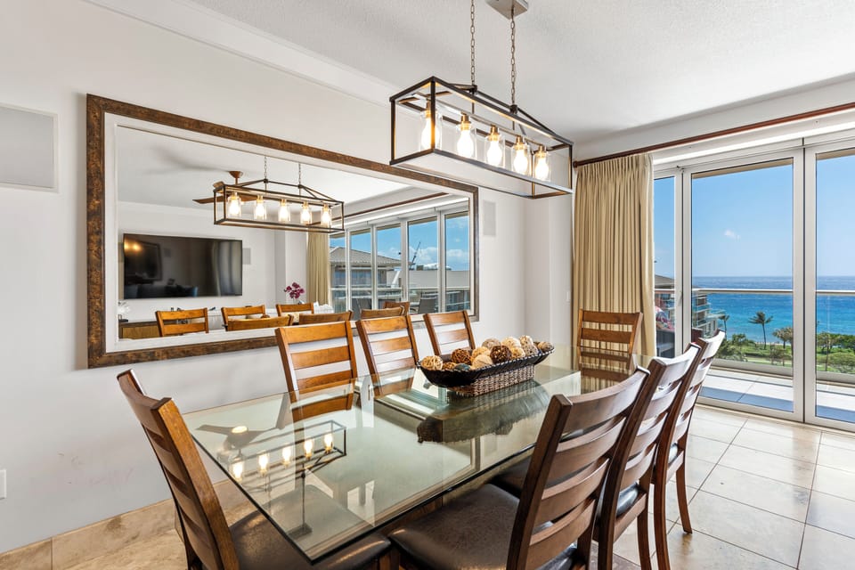 Gather around the spacious table under a modern chandelier, with ocean views just beyond the glass doors