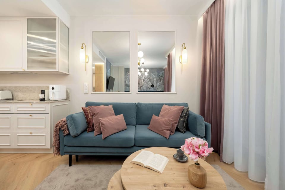 Cozy living area with a teal sofa, soft lighting and large windows with long curtains.
