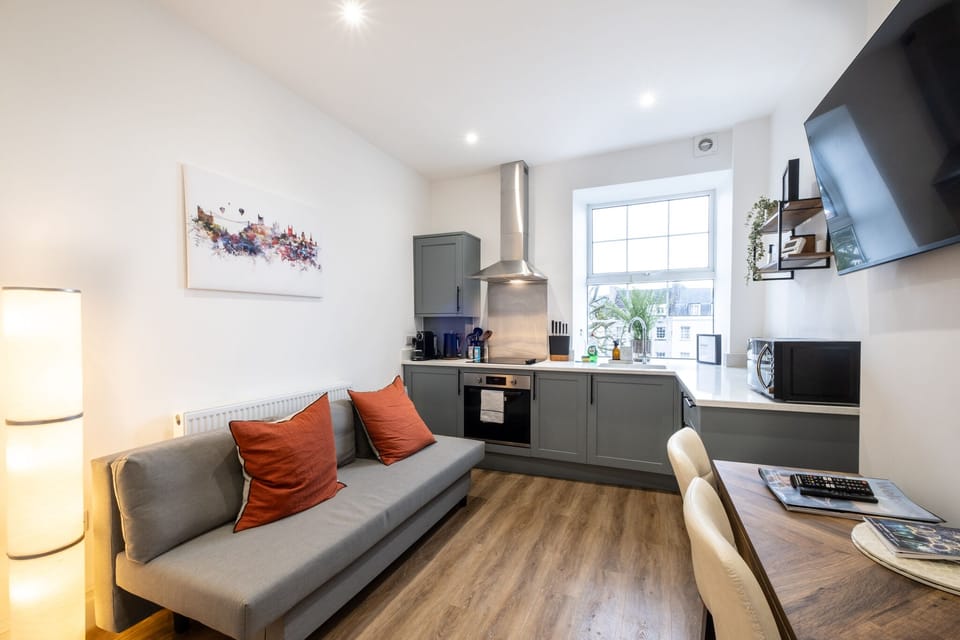 Open-plan kitchen and living area with a cosy sofa and smart TV for relaxing stays.
