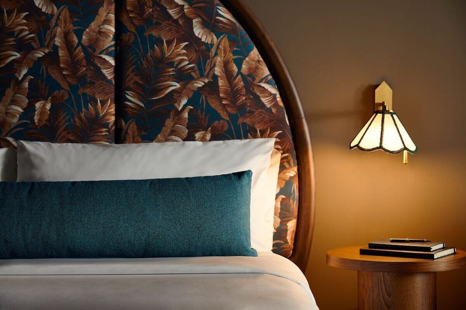 Sink into crisp linens beneath a bold, elegant headboard.