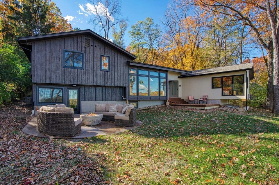Backyard with patio with gas firepit and deck dining space.
