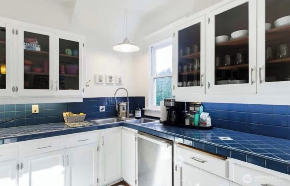 厨房 kitchen
This delightful kitchen perfectly blends classic charm with modern functionality. Featuring striking blue tile countertops and backsplash, the space offers a unique and timeless aesthetic. The crisp white cabinetry with glass-front doors p