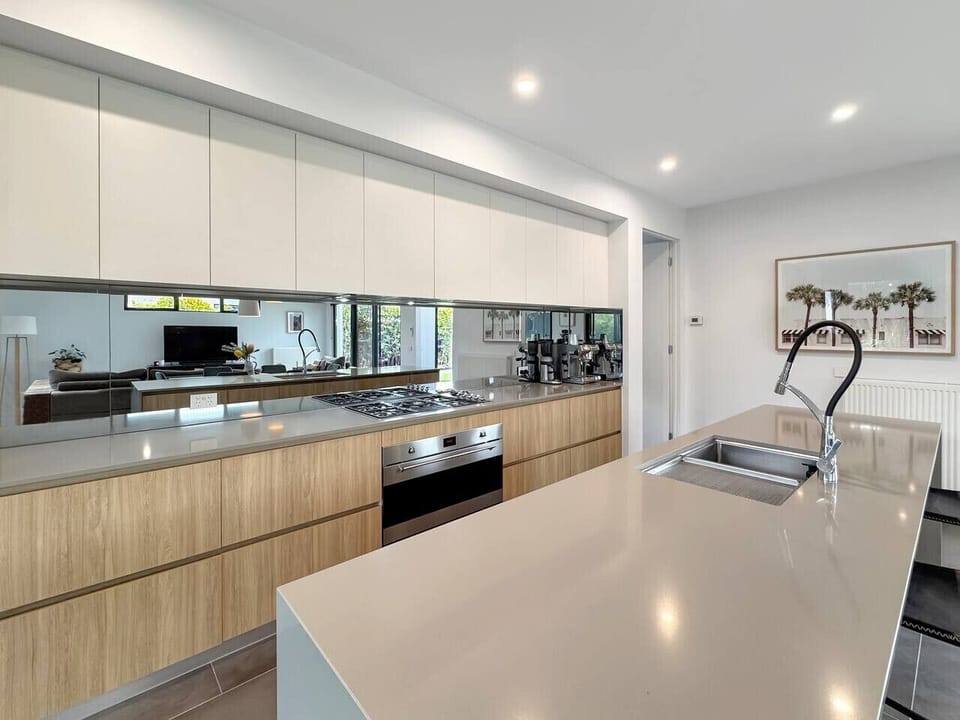 A sleek, modern kitchen with a spacious island, quality appliances and ample bench space, ideal for cooking, gathering and entertaining