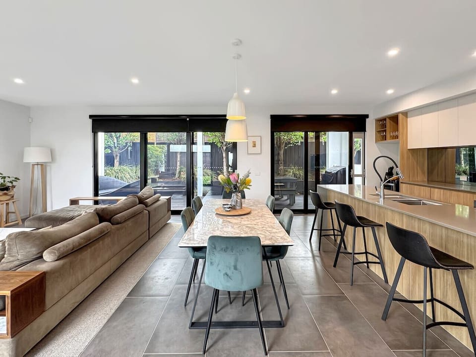 A spacious open-plan living, dining and kitchen area with modern finishes, a large island bench and seamless flow to the outdoor space, perfect for relaxing or entertaining