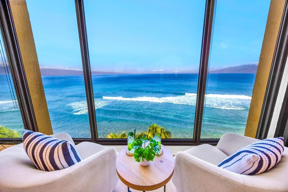 Two lounge chairs by the window invite slow afternoons, with Molokai on the horizon beyond the blue water. MAH-1006