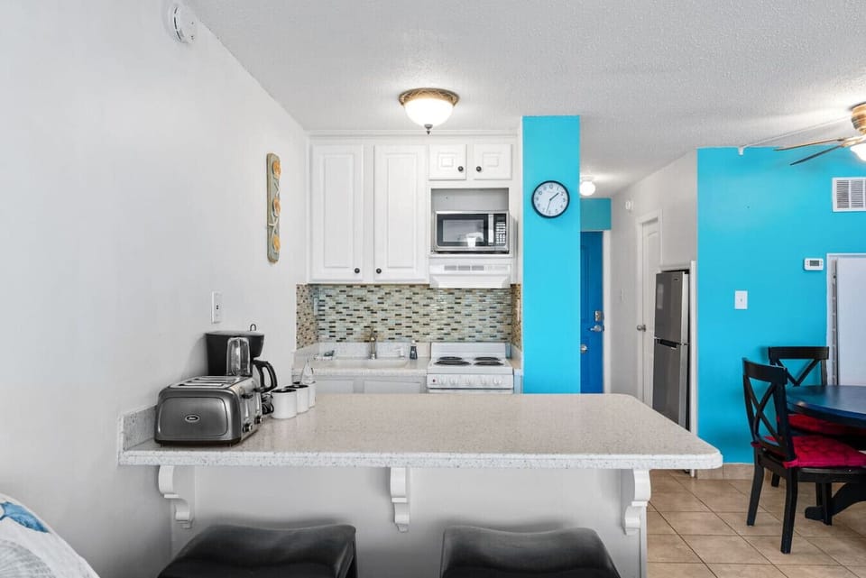 Bright coastal kitchen with bar seating and a fully stocked setup