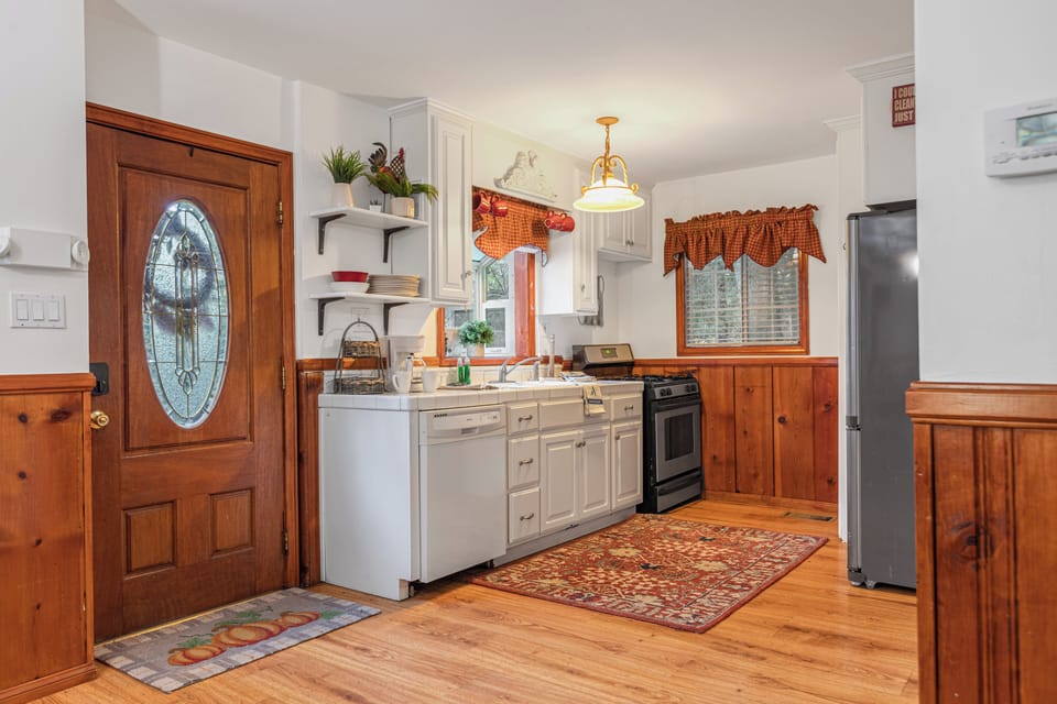 Kitchen with white cabinets, light wood trim, a stainless steel sink, and a patterned rug.