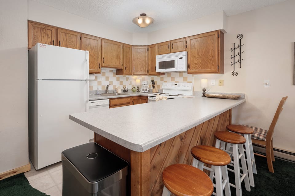 Your fully equipped kitchen features warm wood cabinets, full-size appliances, and a breakfast bar where you'll enjoy morning coffee together.