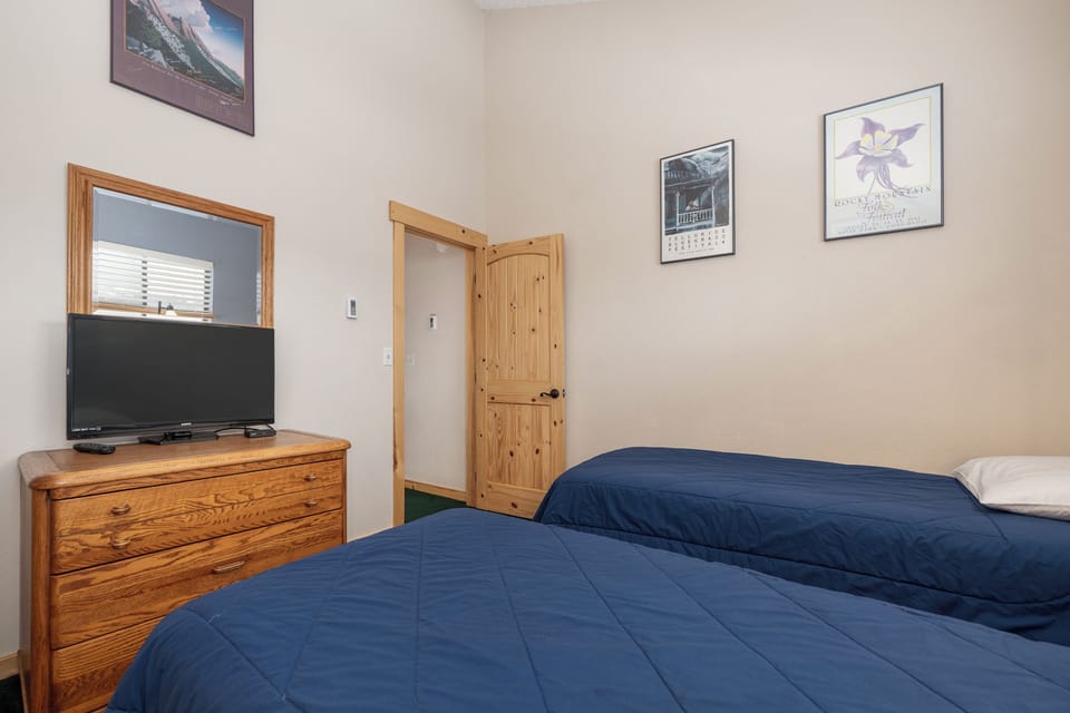 Cozy twin bedroom with comfortable beds, TV, and charming artwork creates your perfect retreat for restful nights.