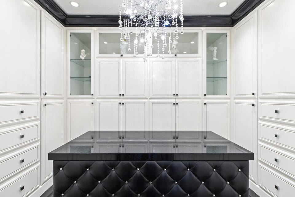 Step into your own boutique-style walk-in closet, complete with custom cabinetry, a sleek island, and a sparkling chandelier — the perfect touch of luxury for your stay.