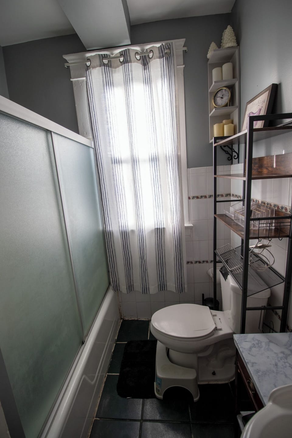 The toilet area includes a tiered shelf unit for holding essential toiletries
