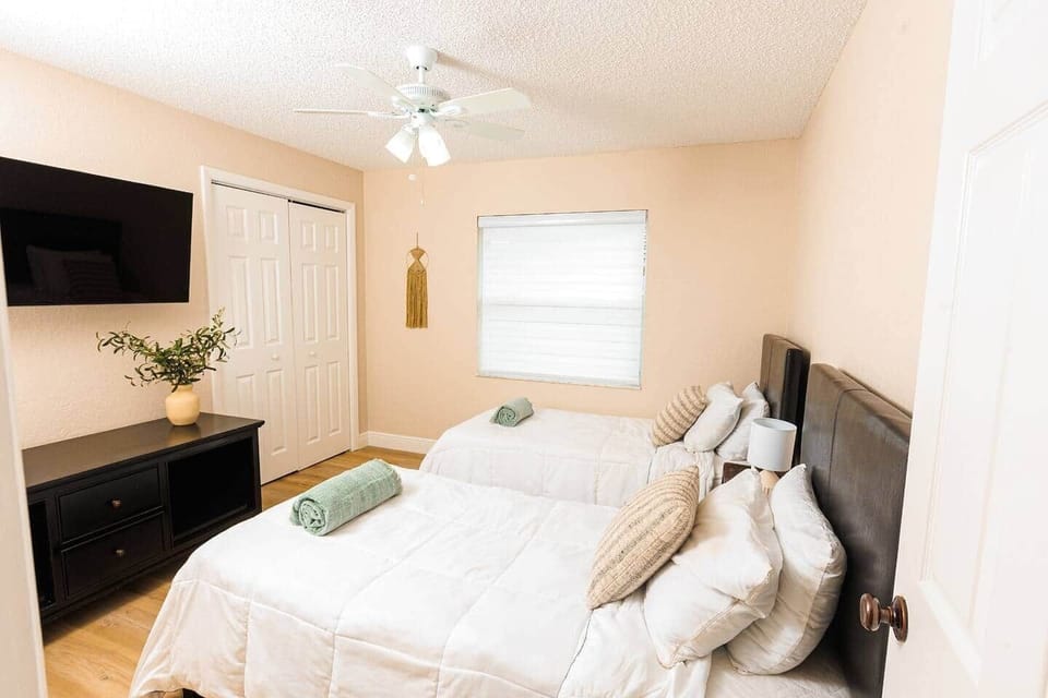 Bedroom four features two single beds, a TV for entertainment, and cozy bed linens. It includes a closet and dresser for storage convenience, making it a cozy retreat for your stay.