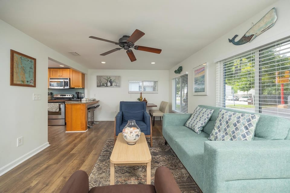 Bright open living space with cozy seating, natural light, and kitchen access