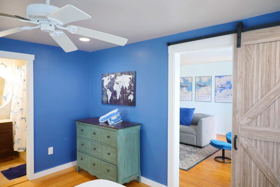 Cozy blue bedroom with warm wood floors and a sliding barn door, simple, inviting, and relaxing.