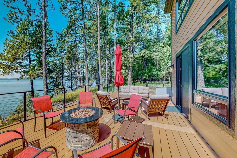 Spacious balcony ideal for relaxing and entertaining, featuring a table and chairs, umbrellas for shade, a fire table, and a propane BBQ.