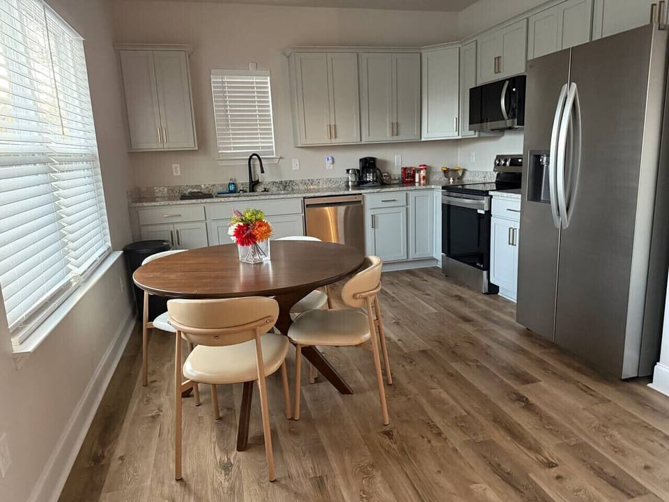 Enjoy a dining table set within a bright, open-concept kitchen—perfect for sharing meals in a clean and inviting space.
