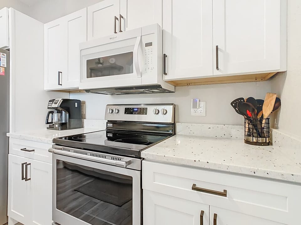 Sleek cooking area with stainless-steel stove, microwave, and a clean, well-organized prep space