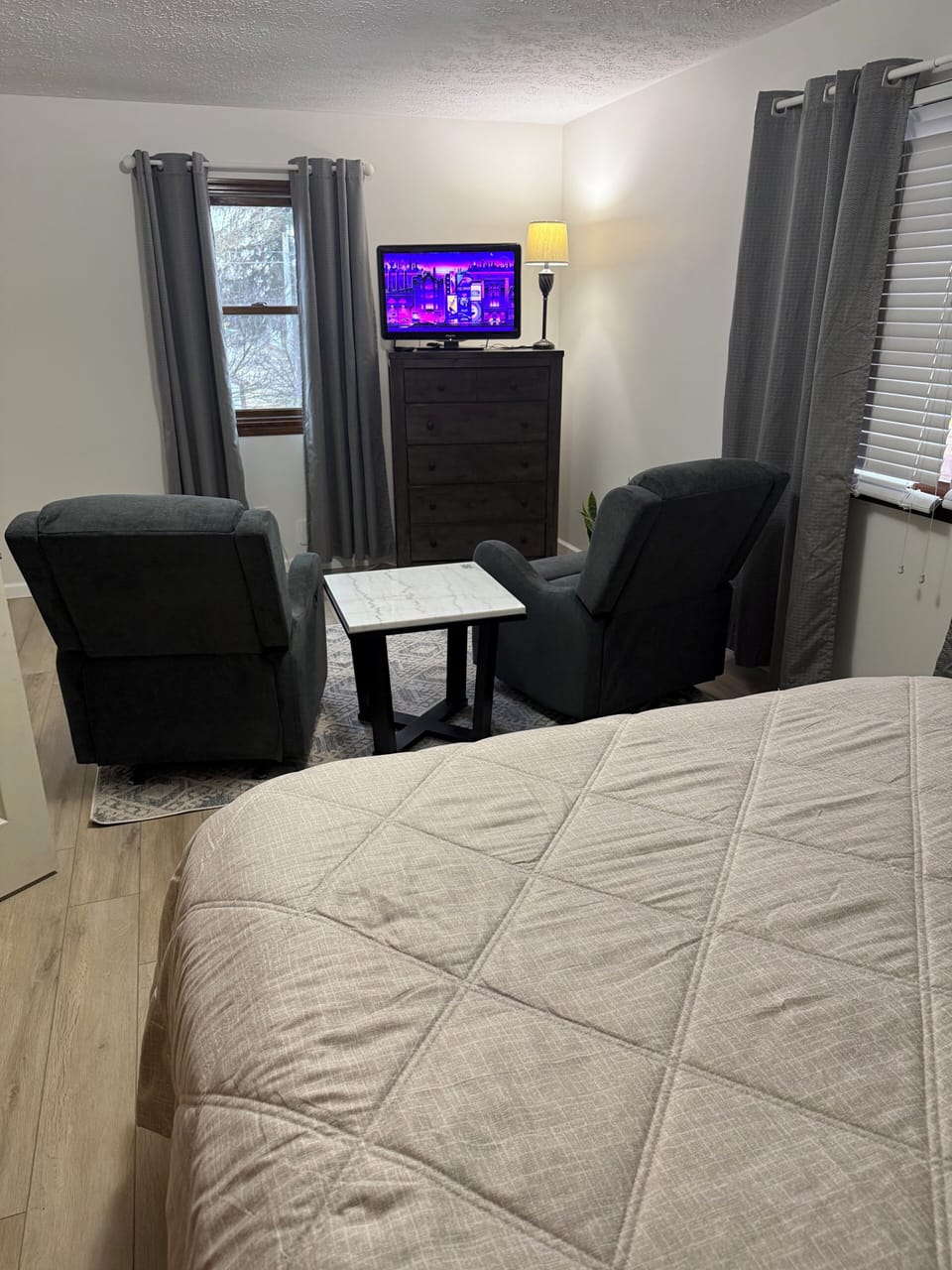 Queen size bed with TV and sitting chairs in bedroom