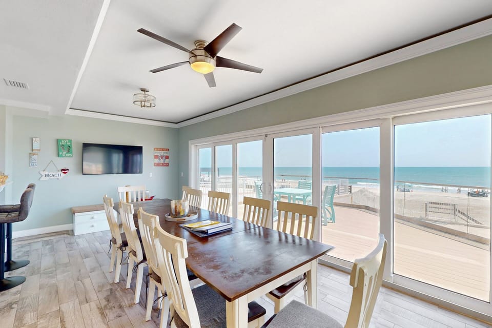 Spacious dining area with large windows overlooking the ocean and direct deck access. Ideal for meals with a view, this inviting space enhances your beach stay with fresh sea breezes and stunning shoreline scenery.