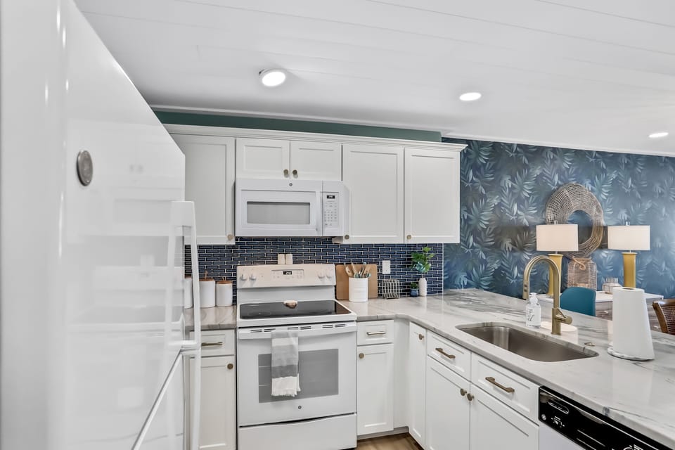 Prepare meals in a bright, coastal kitchen with modern appliances and beach-inspired style. Ideal for your beach stay, this inviting space offers everything needed for easy cooking and relaxed dining after a day by the ocean.