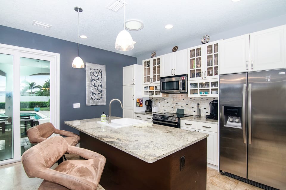 This modern coastal kitchen features granite countertops, stainless steel appliances, and island seating—perfect for easy meals during your beach stay. Bright, open, and designed for relaxing after a day at the shore.