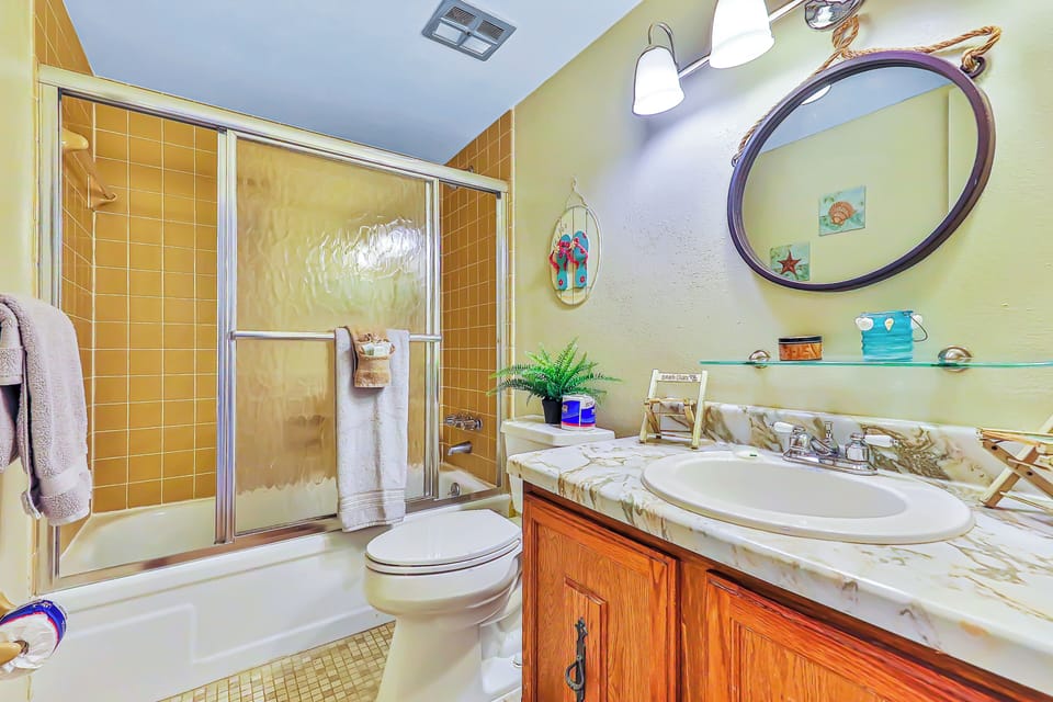 Refresh after a day at the beach in this full bathroom featuring a tub/shower combo, spacious vanity, and beach-inspired décor—perfect for unwinding and getting ready for your next coastal adventure.