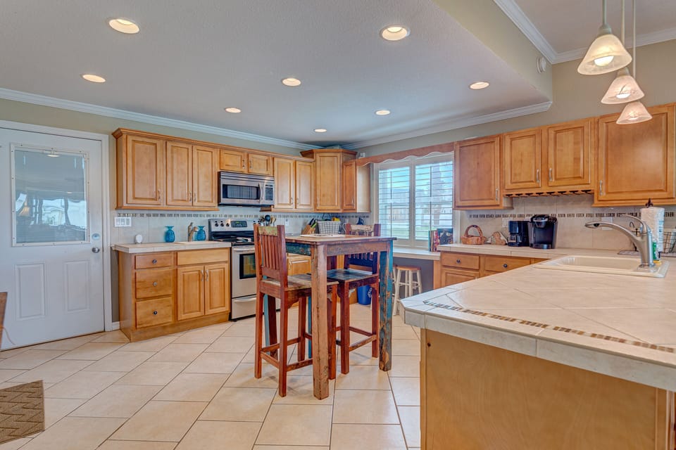 Enjoy this spacious, fully equipped kitchen with coastal charm, ample counter space, and inviting seating. Perfect for cooking and gathering during your beach stay, it's designed for comfort after sunny days by the shore.