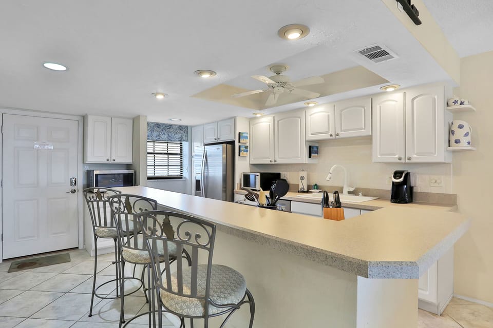This bright coastal kitchen features ample counter space, modern appliances, and comfortable breakfast seating. Ideal for casual meals and gathering with family and friends during your relaxing beach stay.