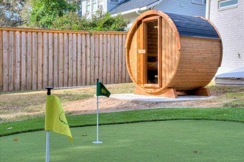 Unique backyard setup showcasing a mini golf area complete with putting flags, alongside a charming barrel-shaped structure that adds a fun and distinctive element to outdoor leisure.
