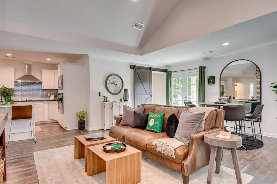 Bright and airy open-concept living space featuring a stylish leather sofa, modern decor, and a cozy dining area on the side.