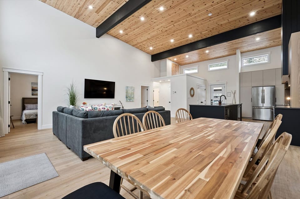 Open-concept great room featuring wood ceilings, exposed beams, and seamless flow between kitchen, dining, and living spaces.