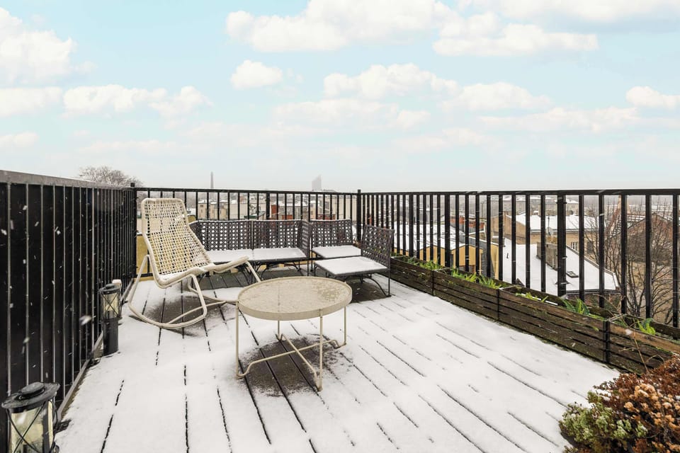 A rooftop terrace with wooden decking and skyline views. Outdoor seating provides a relaxing space.