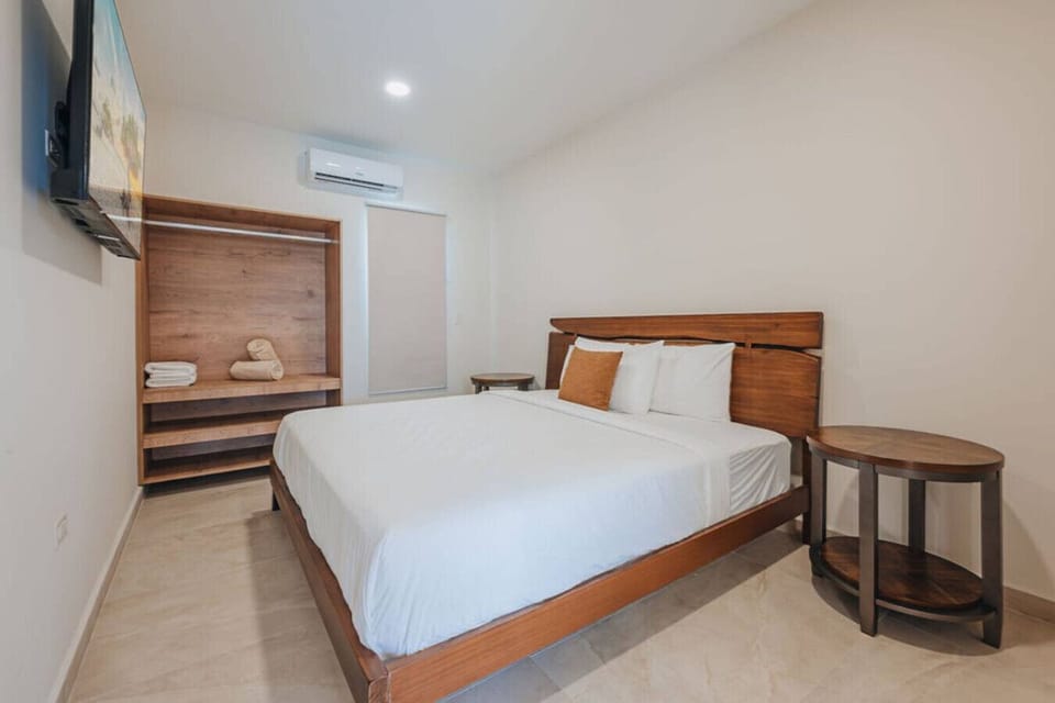 Queen bed, AC, and a mounted Smart TV.
