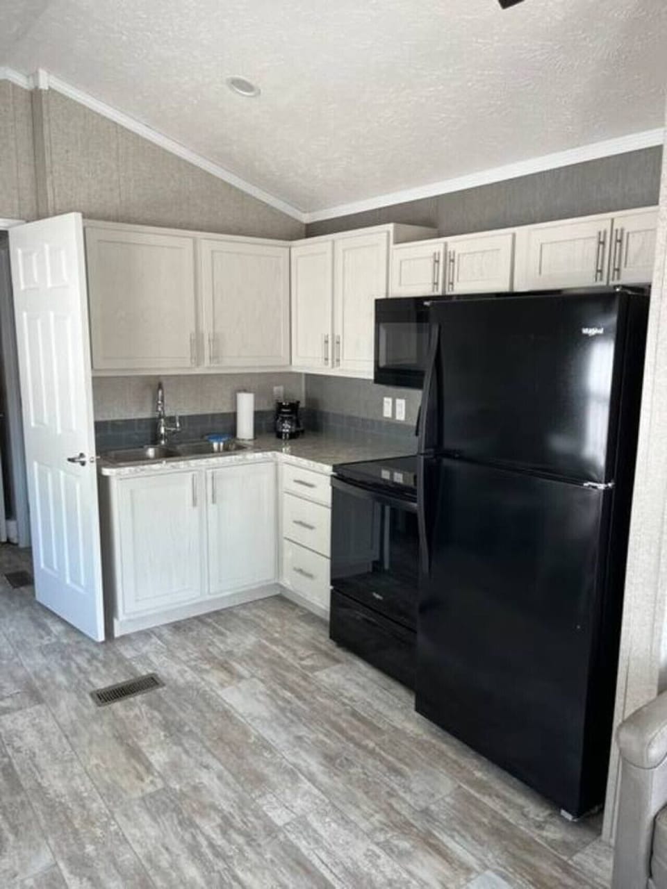 A clean, modern kitchen designed for easy, stress-free cooking. It includes a drip coffee maker, full stove/oven, fridge, and ample cabinet space—all in a sleek, uncluttered layout perfect for simple meals and morning coffee.