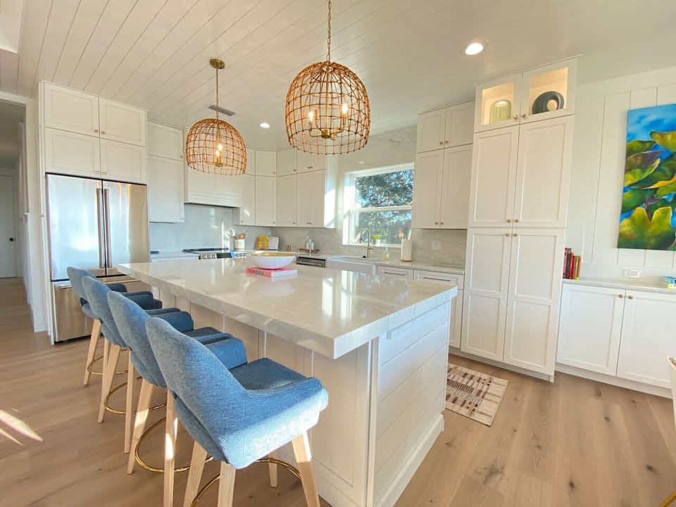 Bright and airy with stainless steel appliances, comfortable bar stools, crisp white cabinetry and countertops...does a kitchen get any better than this?