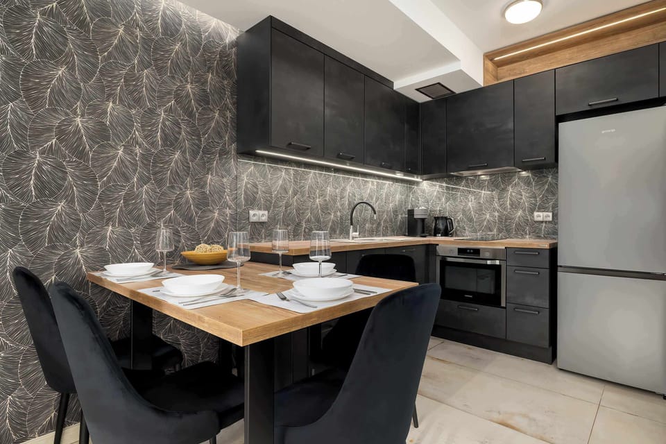 A compact dining–kitchen space with dark cabinetry, a wooden countertop, and a table set for four.