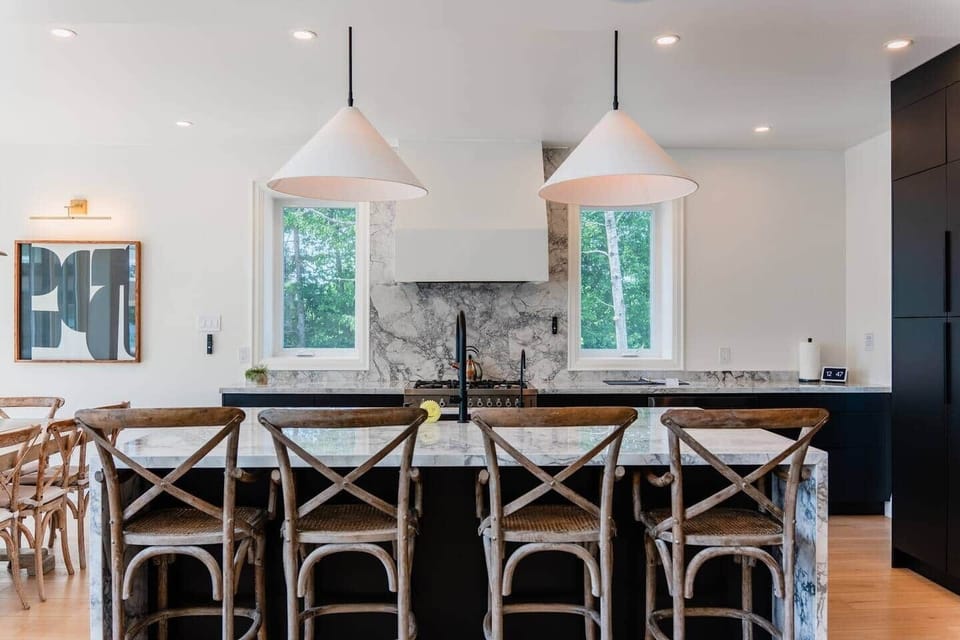 Spacious kitchen with a walk-in pantry, sleek black cabinetry, quartz countertops, and a custom micro-cement range hood.