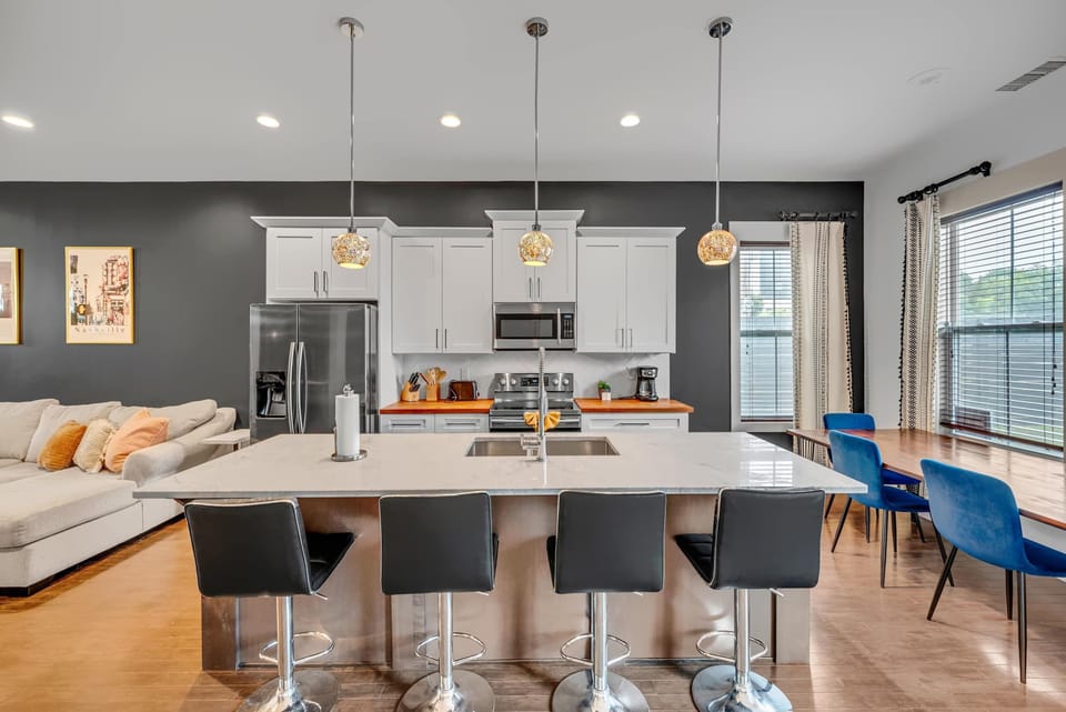Find your dream Nashville vacation rental! This stylish kitchen is ideal for large groups, featuring modern decor and ample seating. Enjoy your morning coffee at the sleek island before exploring the city. Experience comfort and luxury during your getaway!