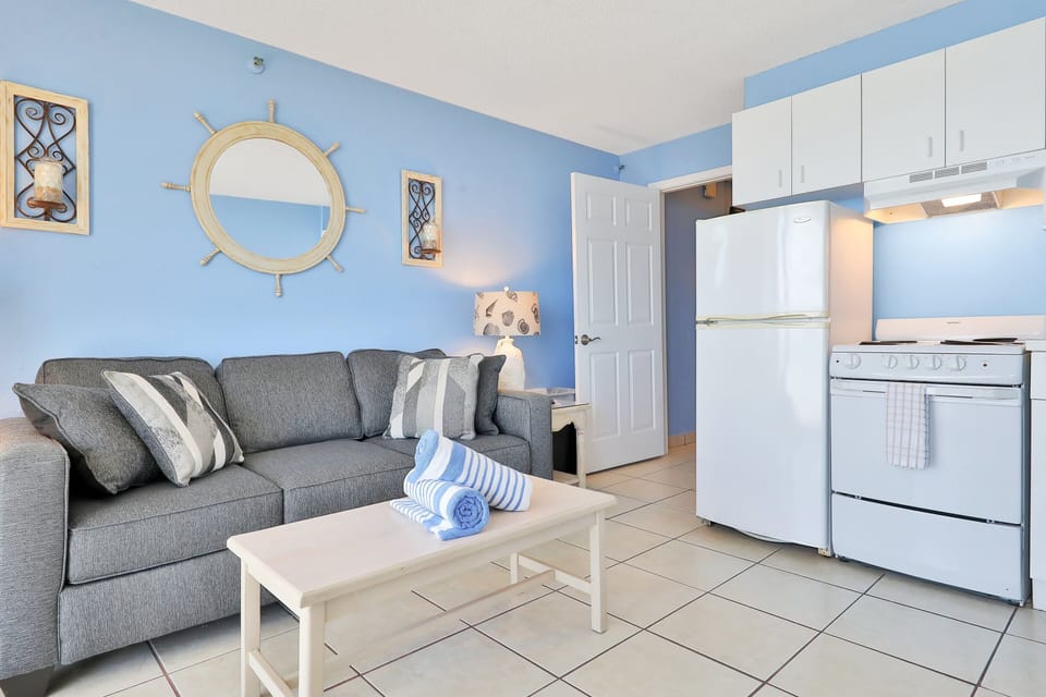 Enjoy your beach stay in this bright coastal living area featuring comfortable seating and a fully equipped kitchen. Perfect for relaxing, dining, and recharging between sunny days at the beach.