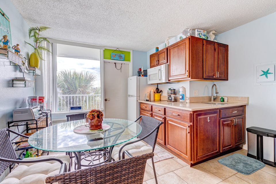 This fully equipped, beach-inspired kitchen and dining area offers bright natural light and coastal charm—perfect for casual meals and relaxing moments during your comfortable beach stay.