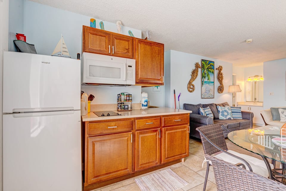 Enjoy this bright, beach-inspired kitchen flowing into the living area, featuring modern appliances and coastal charm—perfect for easy meals, relaxing evenings, and making the most of your beach stay.