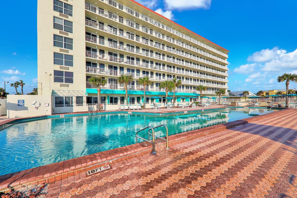 Cool off during your beach stay at this spacious resort-style pool surrounded by palm trees and lounge seating—perfect for relaxing, swimming, and soaking up the coastal sunshine just steps from the beach.