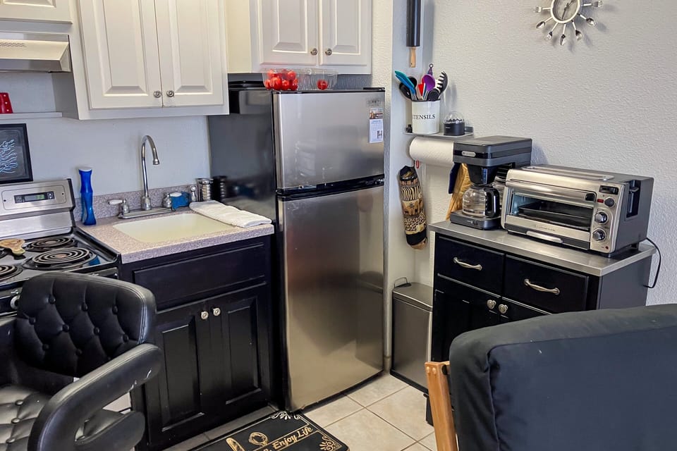 Convenient beachside kitchen featuring full-size fridge, stove, coffee maker, and essentials. Ideal for preparing meals after the beach and enjoying a comfortable, home-like coastal stay.