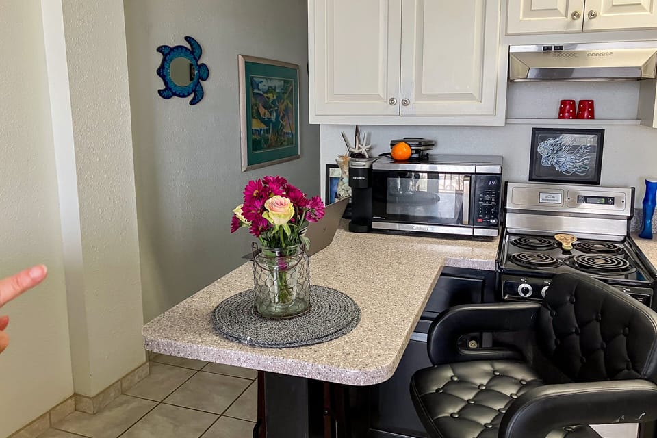 Fully equipped kitchenette with breakfast bar, coffee maker, and coastal accents. Perfect for quick meals between beach adventures and relaxing mornings during your comfortable seaside beach stay.