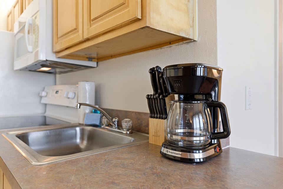 Start your morning with fresh coffee in this convenient beach condo kitchen featuring a coffee maker, sink, and essential appliances. Perfect for fueling up before a relaxing beach stay filled with sun, sand, and ocean breezes.