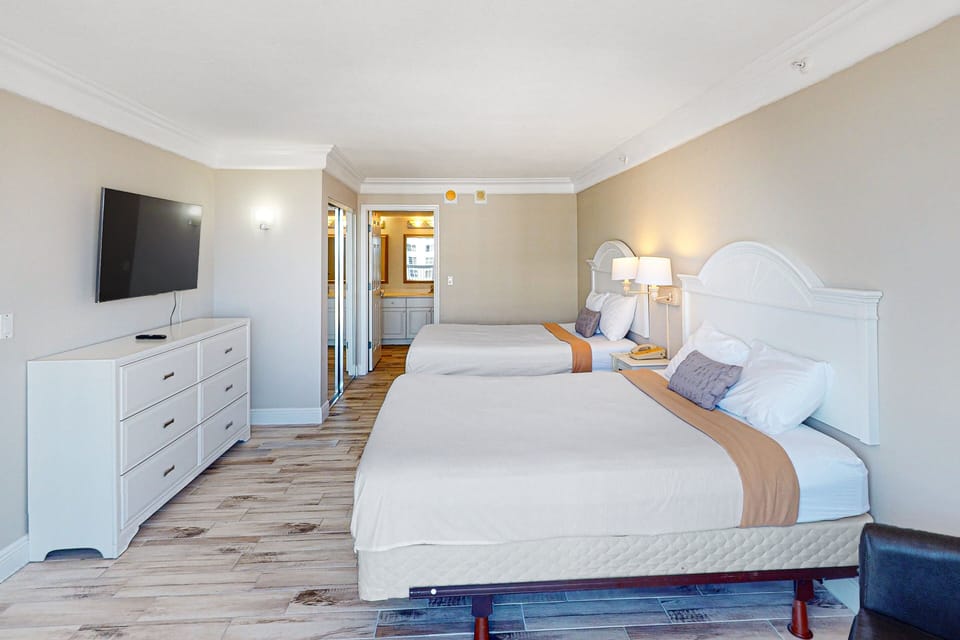 Spacious beachside room featuring two comfy beds, fresh coastal décor, and a large TV. Enjoy plenty of natural light and easy access to your relaxing ocean-view stay.