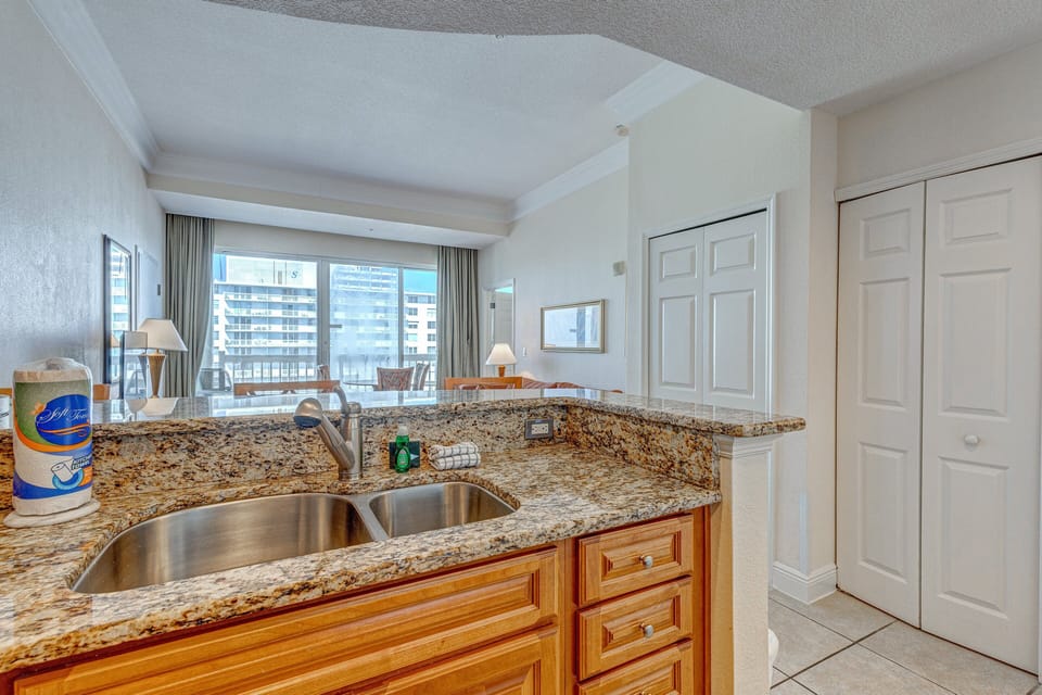This bright beach-stay kitchen features granite counters, double sink, and open sightlines to the living area and coastal views—perfect for prepping meals during your seaside getaway.