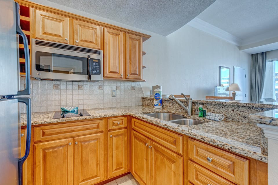This fully equipped beach-stay kitchen features granite counters, stainless appliances, and ample cabinet space—ideal for preparing meals after a day on the sand and surf.